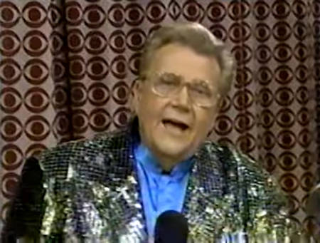 Rod is wearing a gold sequined jacket & blue collarless silk shirt with matching pocket square