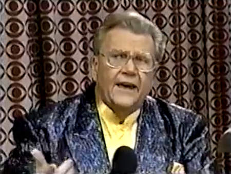 Rod is wearing a black/purple sequined jacket & yellow collarless silk shirt with matching pocket square