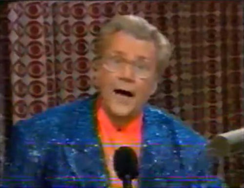Rod is wearing a blue sequined jacket & salmon collarless silk shirt