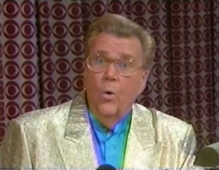 Rod is wearing a shiny gold jacket & light-blue collarless silk shirt