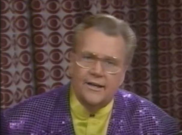 Rod is wearing a purple sequined jacket & yellow collarless silk shirt