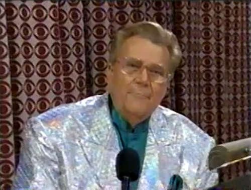Rod is wearing a shiny silver jacket & seafoam-green collarless silk shirt with matching pocketsquare