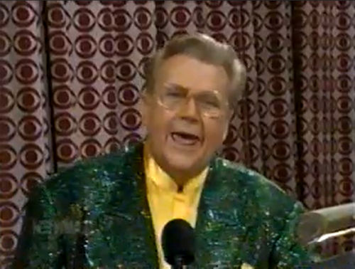Rod is wearing a dark-green sequined jacket & yellow collarless silk shirt with matching pocket square