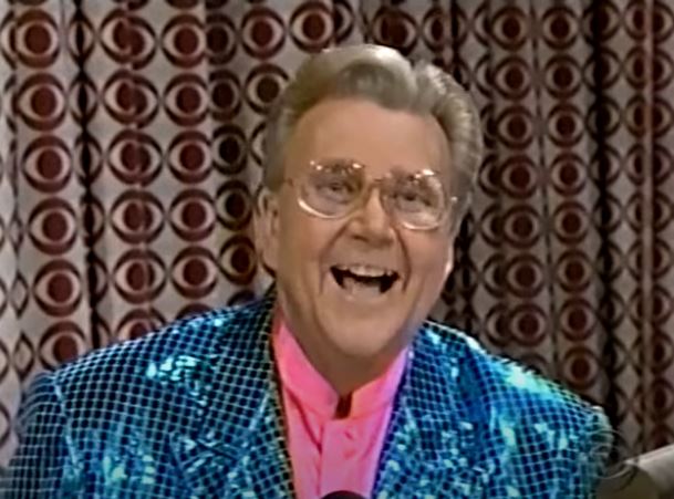 Rod is wearing a blue sequined jacket & pink collarless silk shirt