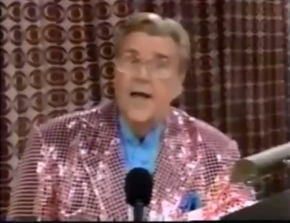 Rod is wearing a pink sequined jacket & light-blue collarless silk shirt with matching pocket square