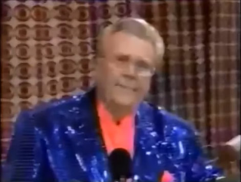 Rod is wearing a blue sequined jacket & salmon collarless silk shirt with matching pocketsquare