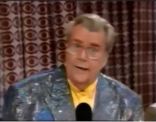 Rod is wearing a gray sequined jacket & yellow collarless silk shirt