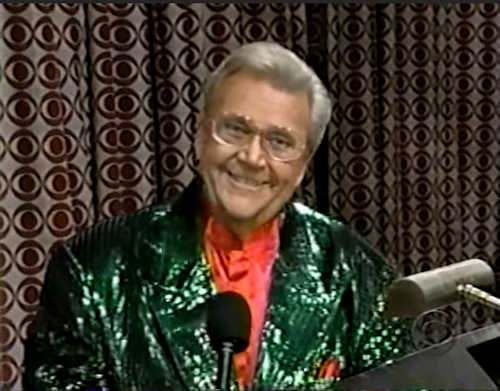 Rod is wearing a dark-green sequined jacket & salmon collarless silk shirt with matching pocket square