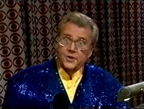 Rod is wearing a blue sequined jacket & yellow collarless silk shirt