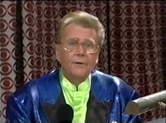 Rod is wearing a shiny blue jacket with black lapels & lime-green collarless silk shirt