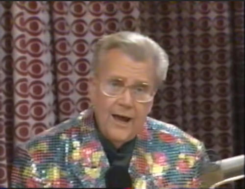 Rod is wearing a blue/red/yellow sequined jacket & black collarless silk shirt