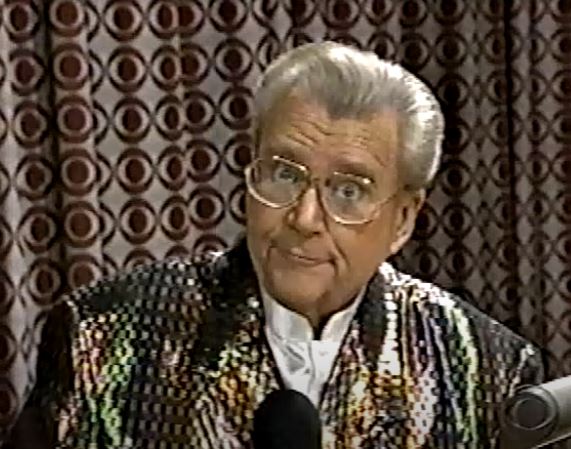 Rod is wearing an irredescent jacket & white collarless silk shirt