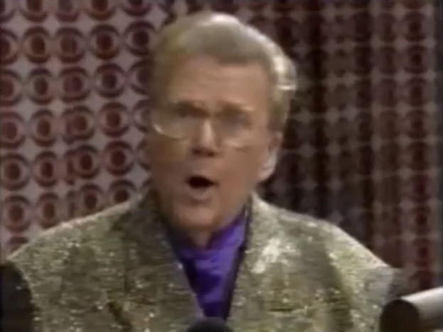 Rod is wearing a gold sequined jacket & purple collarless silk shirt
