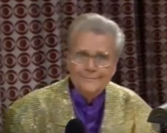 Rod is wearing a gold sequined jacket & purple collarless silk shirt