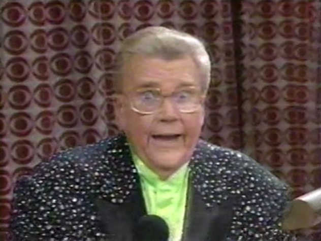 Rod is wearing a black jacket with white speckles, black lapels  & lime-green collarless silk shirt