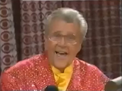 Rod is wearing a peach sequined jacket & yellow collarless silk shirt