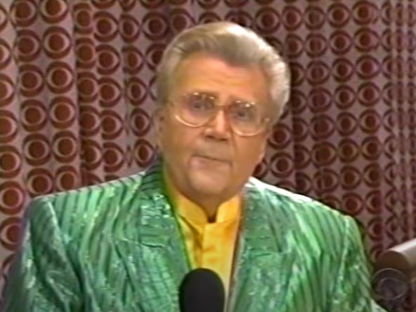 Rod is wearing a shiny green/green-striped jacket & yellow collarless silk shirt