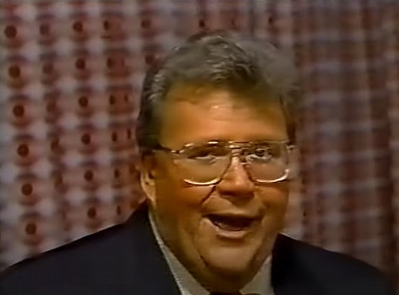 Rod is wearing a black jacket, white shirt & red neck tie