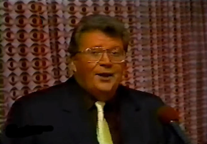 Rod is wearing a black jacket, yellow tie & burgandy shirt