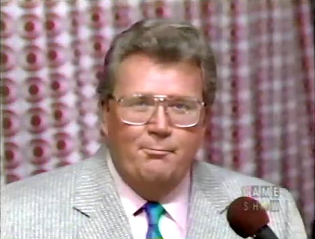 Rod is wearing a black jacket, dark-purple shirt & yellow silk tie