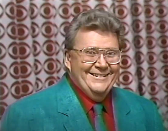 Rod is wearing a green jacket & tie & a red shirt