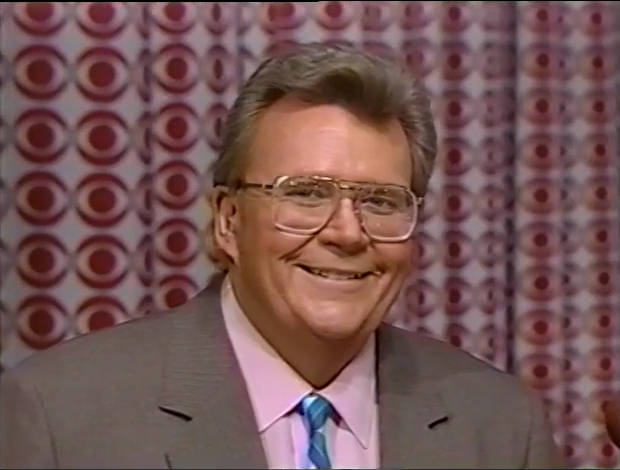 Rod is wearing a tan jacket blue/purple/white-striped tie & pink shirt