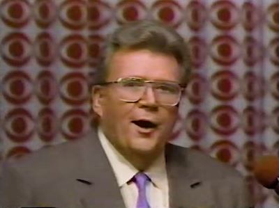 Rod is wearing a brown jacket, purple necktie & cream shirt