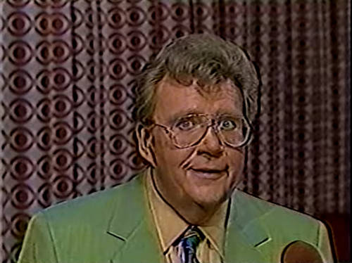 Rod is wearing a pear-green jacket, patterned neck tie & mustard-yellow shirt