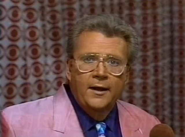 Rod is wearing a pink jacket, navy shirt & mottled-tie