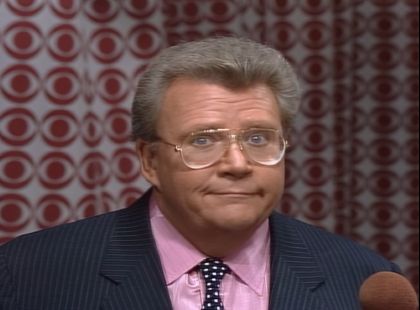 Rod is wearing a black pin-striped jacket, pink silk shirt & a black neck tie with white polka dots