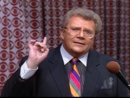 Rod is wearing a black jacket, multi-colored striped necktie and black/white pinstripe shirt with matching pocket square