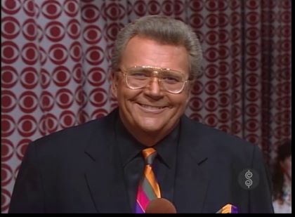 Rod is wearing a black jacket, black shirt & multi-colored striped tie with matching pocket square