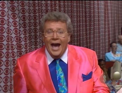 Rod is wearing a pink silk jacket, dark-blue shirt with white collar, matching pocketsquare and mottled neck tie