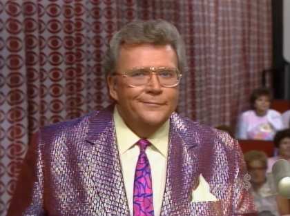Rod is wearing a shimmery pink/purple jacket, fuchsia/blue neck tie and cream shirt with matching pocket square