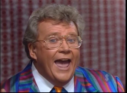 Rod is wearing a multi-colored striped jacket, orange necktie & a blue shirt with a white collar