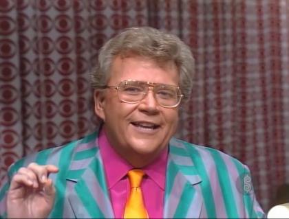 Rod is wearing a green and grey striped jacket, fuchsia shirt & gold necktie