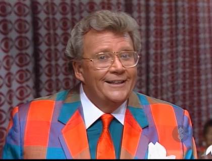 Rod is wearing a red/orange/blue/purple checked jacket, red necktie & blue-green shirt with a white collar