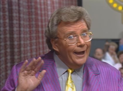 Rod is wearing a purple jacket, gold silk tie & grey shirt