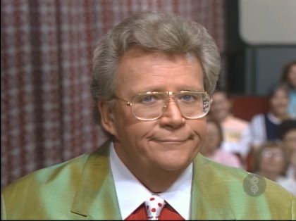 Rod is wearing an olive-green jacket, red tuxedo shirt with a white collar & a white necktie with red polka dots