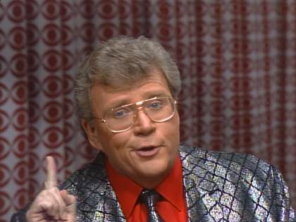 Rod is wearing a silver-square patterned jacket, matching necktie & red shirt
