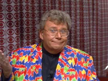 Rod is wearing a southwest-style patterned jacket & navy-blue collarless shirt