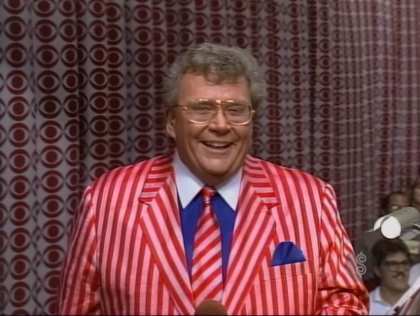 Rod is wearing a red & white striped jacket with matching necktie & a blue shirt with white collar & matching pocket square