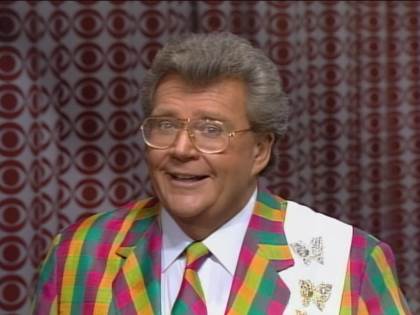Rod is wearing a multi-colored gingham jacket, matching necktie, white shirt & white sash with gold butterflies