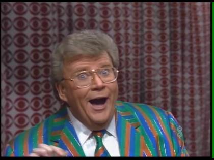 Rod is wearing a blue/green/orange striped jacket, matching necktie & white tuxedo shirt