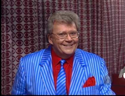 Rod is wearing a blue and grey striped jacket, matching necktie & a red shirt with matching pocket square
