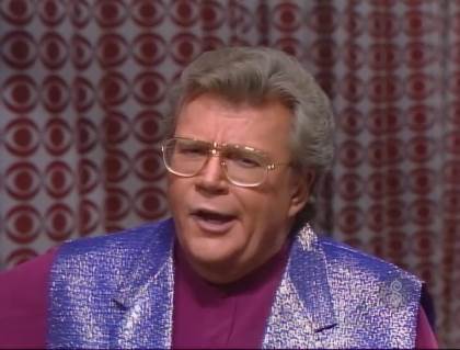 Rod is wearing a shiny purple vest & purple collarless shirt