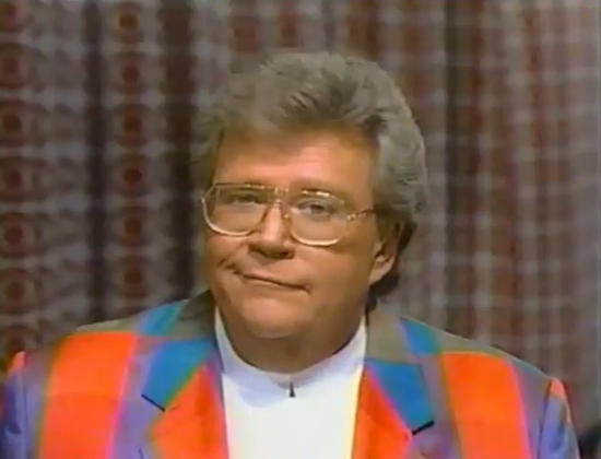 Rod is wearing a multi-colored 'patchwork' jacket & white collarless shirt