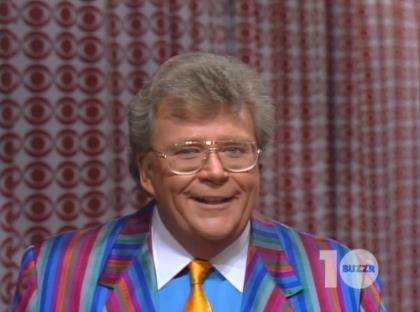 Rod is wearing a rainbow-striped jacket, gold necktie, light-blue shirt with white collar