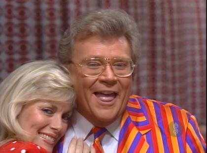 Rod is wearing an orange-red-purple-striped jacket with matching necktie & a white shirt with matching pocket square