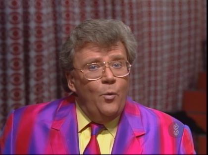 Rod is wearing a purple & pink striped jacket, matching necktie & a yellow shirt